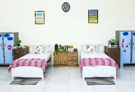 A DWPS hostel room with two beds, bedside cupboards and a shared table between them