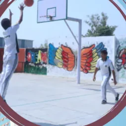 A pupil shooting at the basketball hoop on the outdoor court