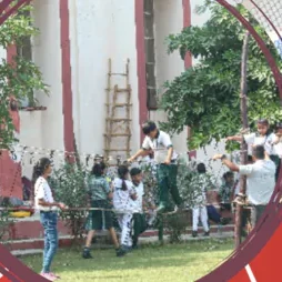 Pupils on a wooden ladder climbing frame beside the building