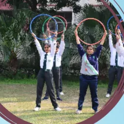 Pupils holding hoops above their heads during a drill on the lawn