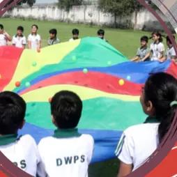 Pupils in DWPS kit gathered around a coloured parachute game