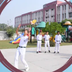 A pupil holding a coloured parachute on the play area, with others watching