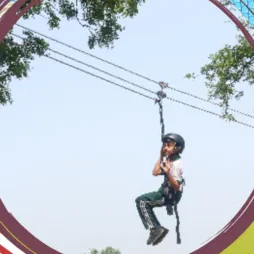 A pupil in a helmet and harness riding the zip line